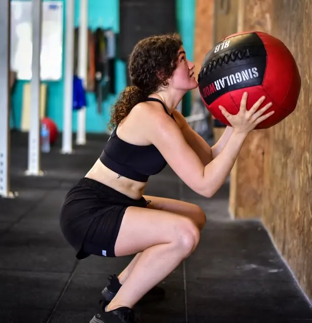 Atleta lanzando un balón medicinal a la pared